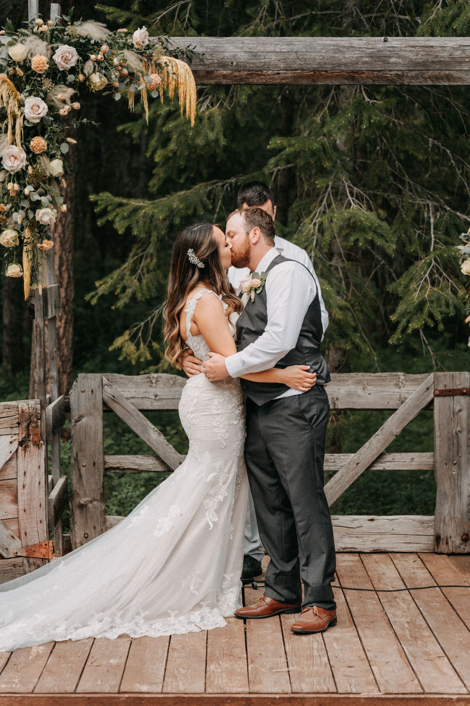 A romantic wedding moment on a rustic wooden deck decorated with blush flowers captured by wedding videographer Jovan Films.