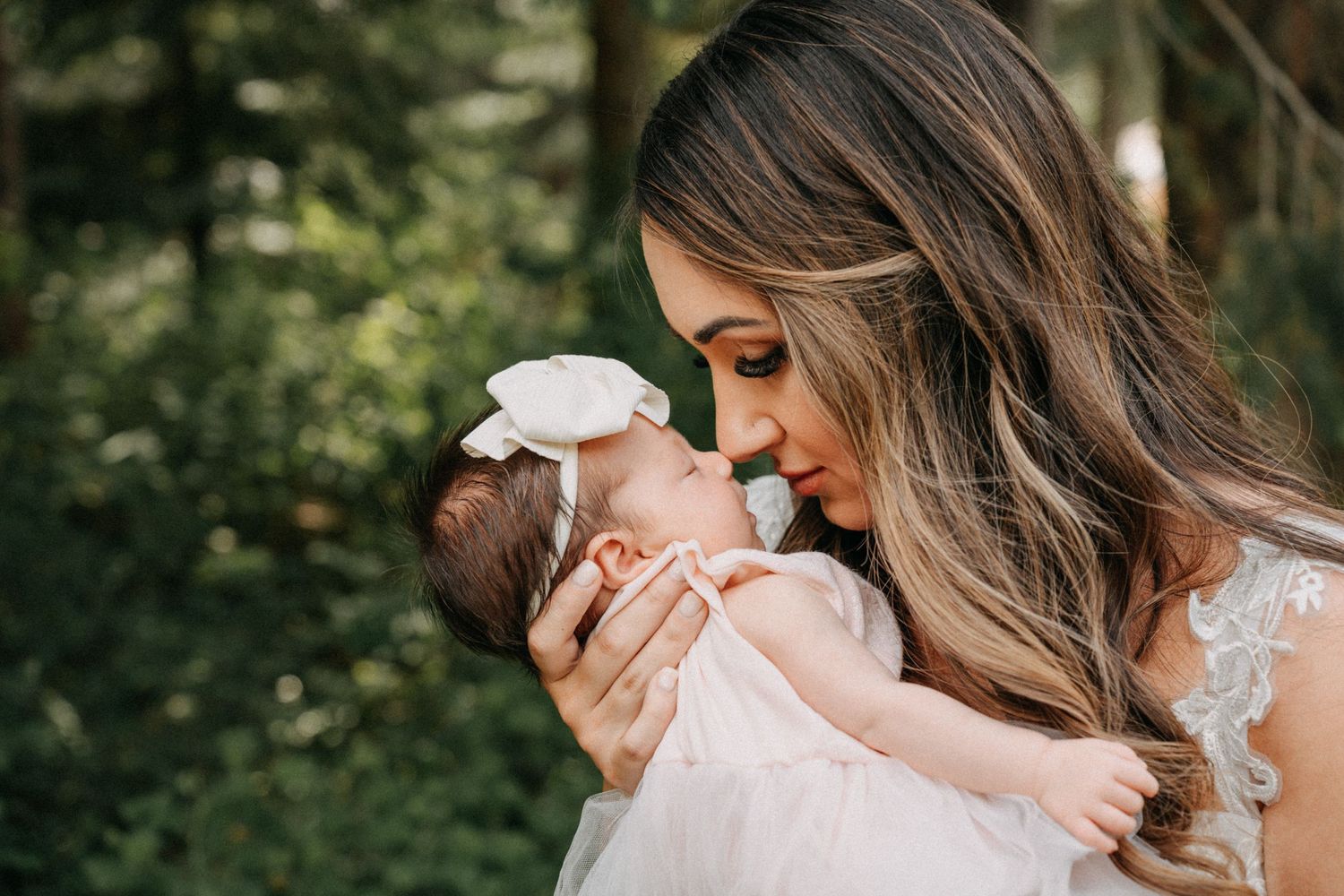 A tender moment captured in a forest setting with mother and baby in pink captured by wedding videographer Jovan Films.