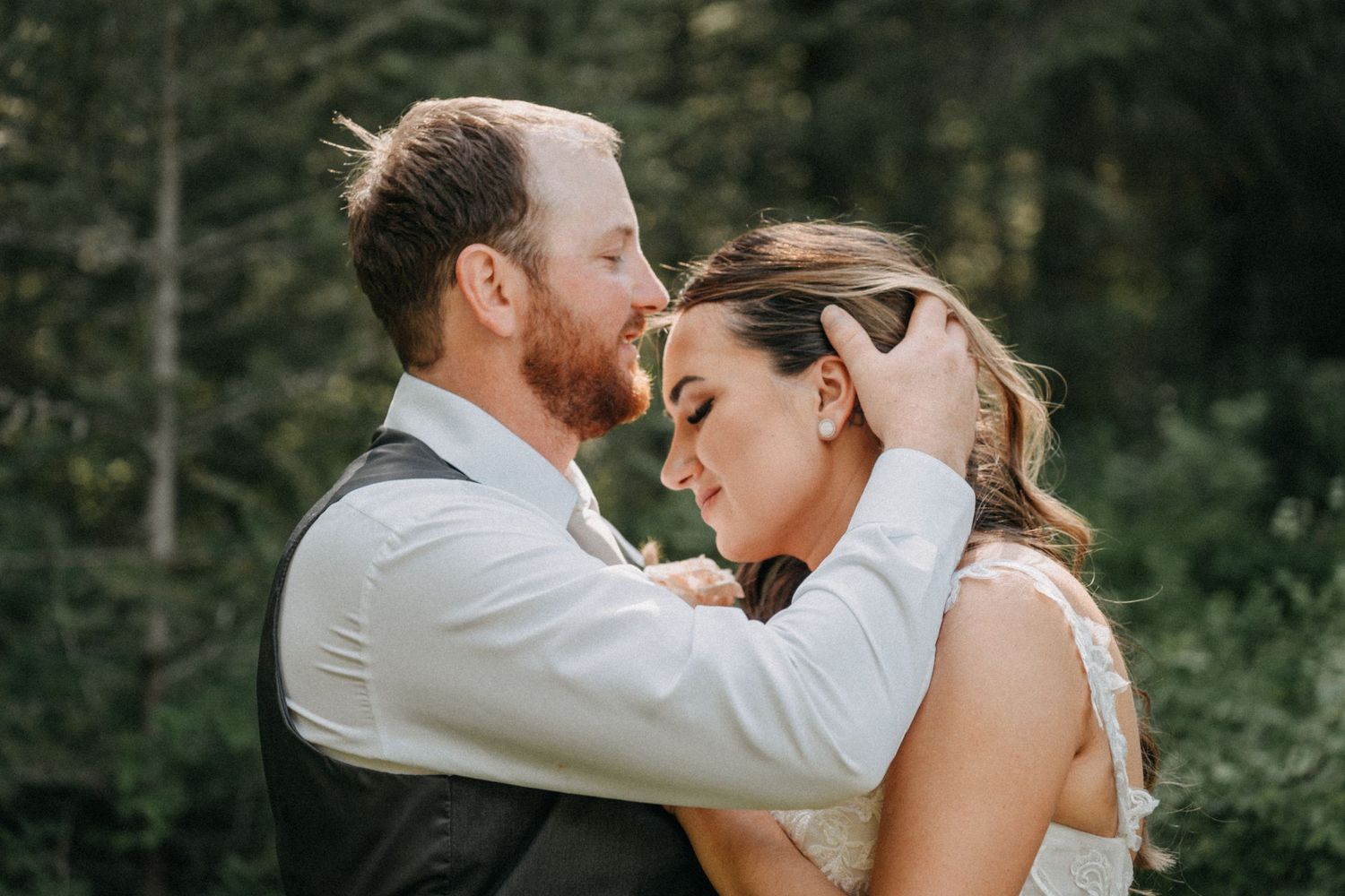 A loving couple shares an intimate moment together during a wedding photoshoot in a lush forest captured by wedding videographer Jovan Films