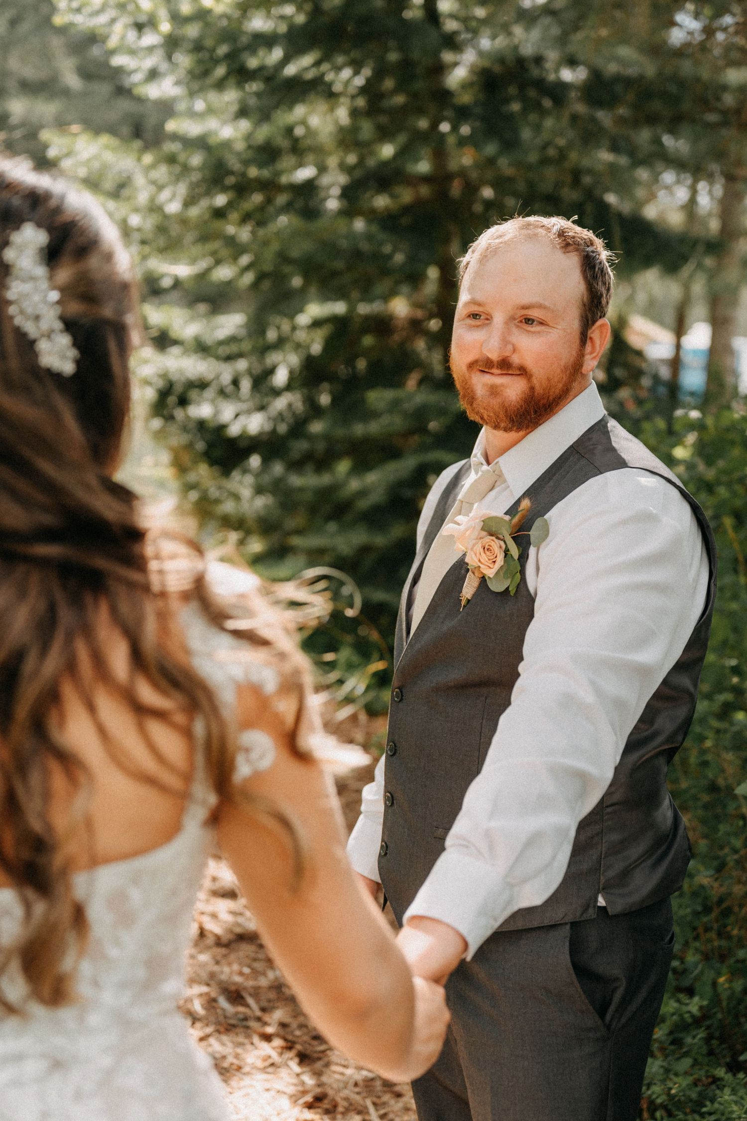 A groom in a grey vest and white shirt smiles joyfully during a wedding ceremony captured by wedding videographer Jovan Films.