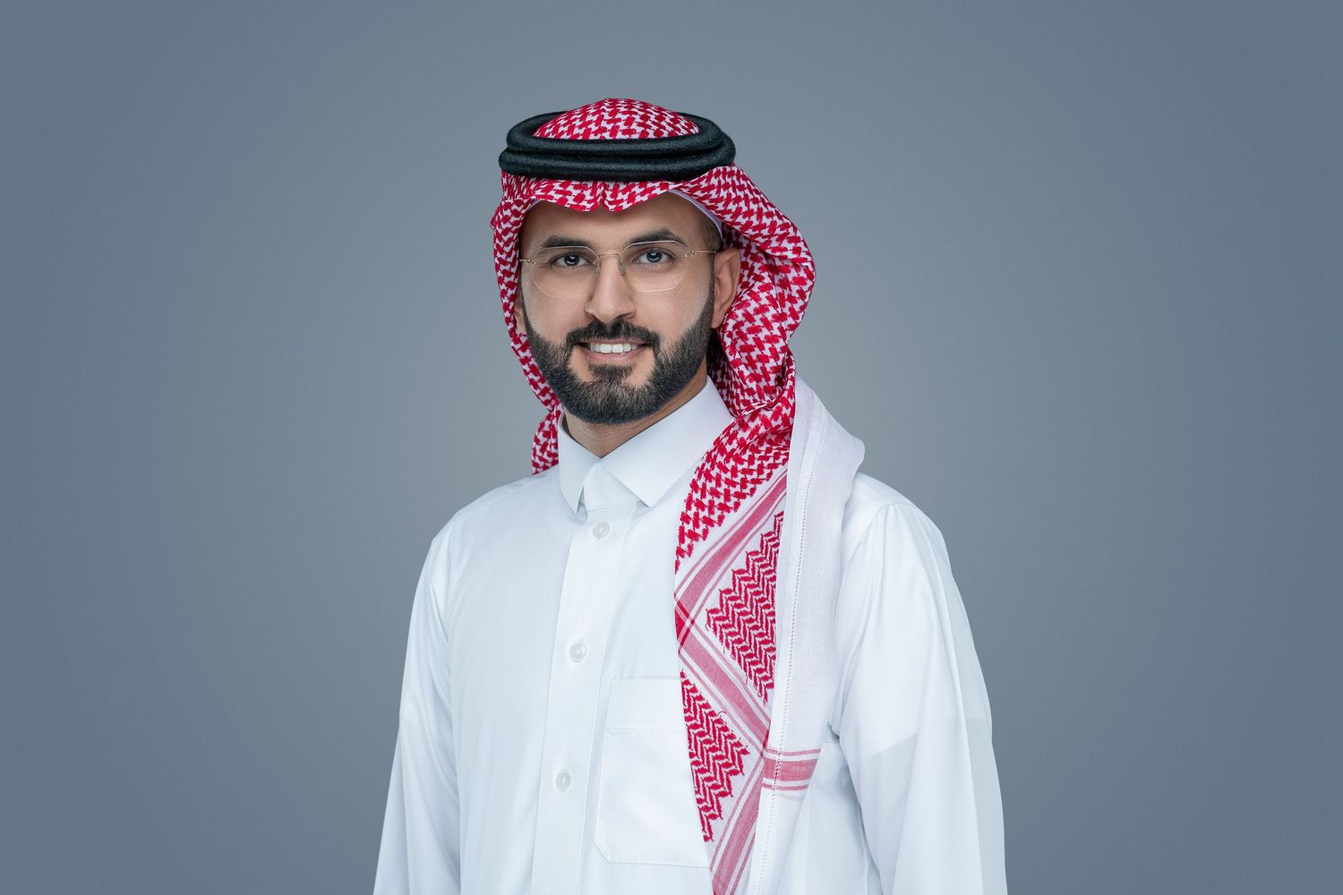 Professional portrait of a person wearing traditional Middle Eastern white thobe and red and white checkered keffiyeh headdress.