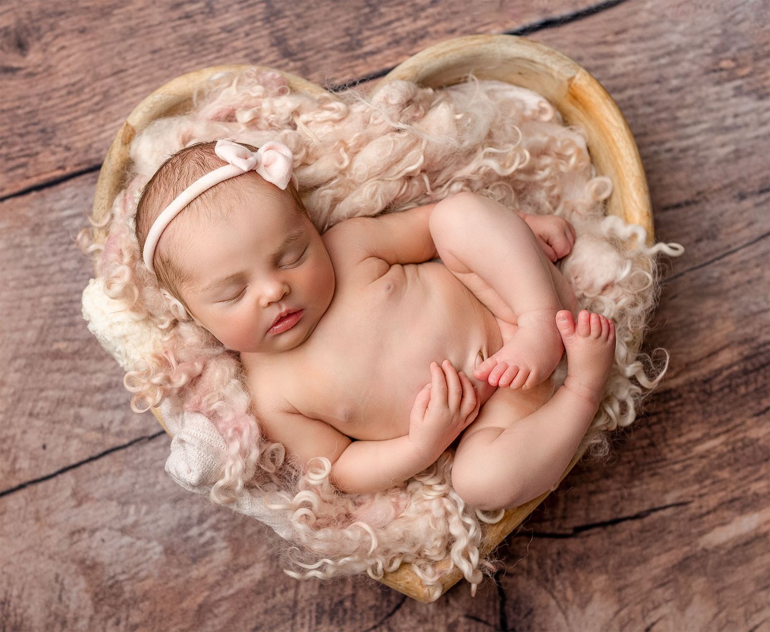 A safely posed baby in a heart bowl capturing delicate features in a dreamy setting giving a timeless look