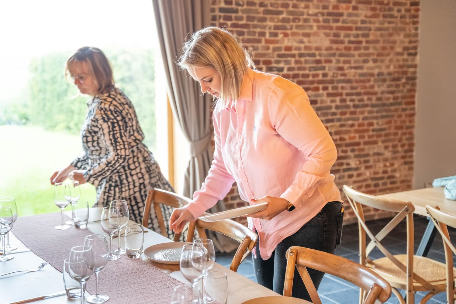 Event setup in progress at rustic brick venue with elegant table settings.