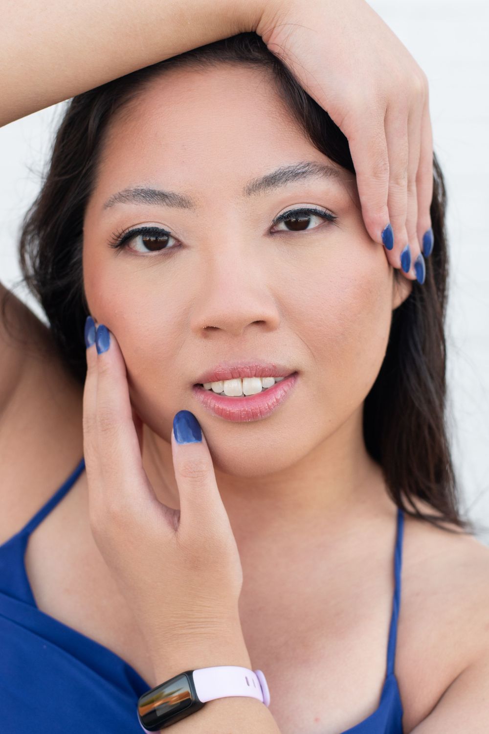 Close-up portrait showing blue nail polish and smart watch accessory.