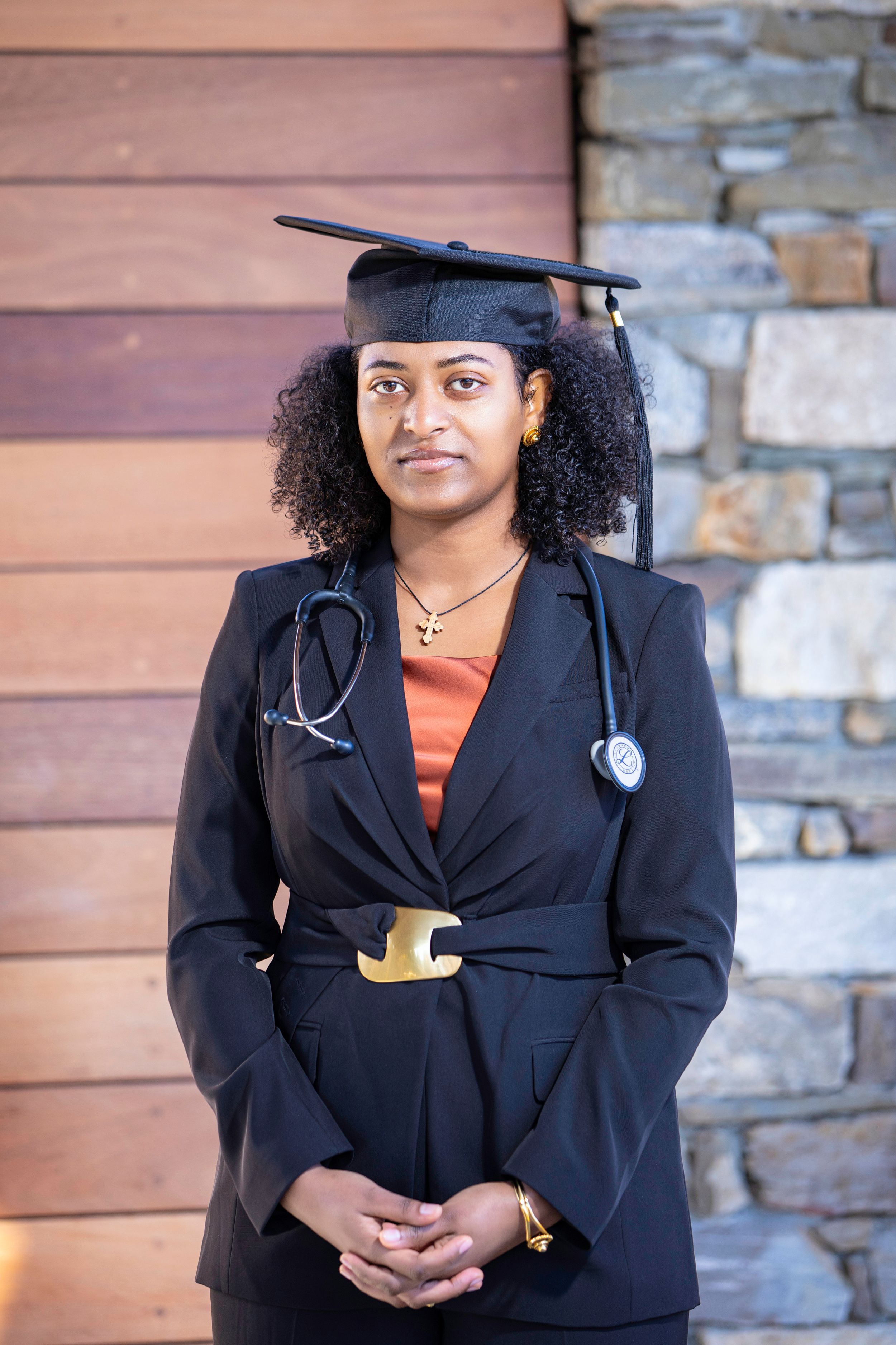 Medical graduate in professional attire with stethoscope and graduation cap.