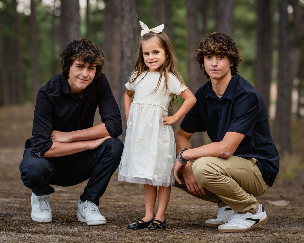 A series of outdoor family portrait poses in a peaceful forest setting with navy blue and white coordinated outfits.