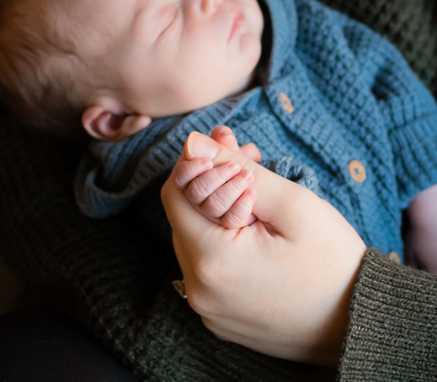 mother holding infants hand for a newborn family photo session