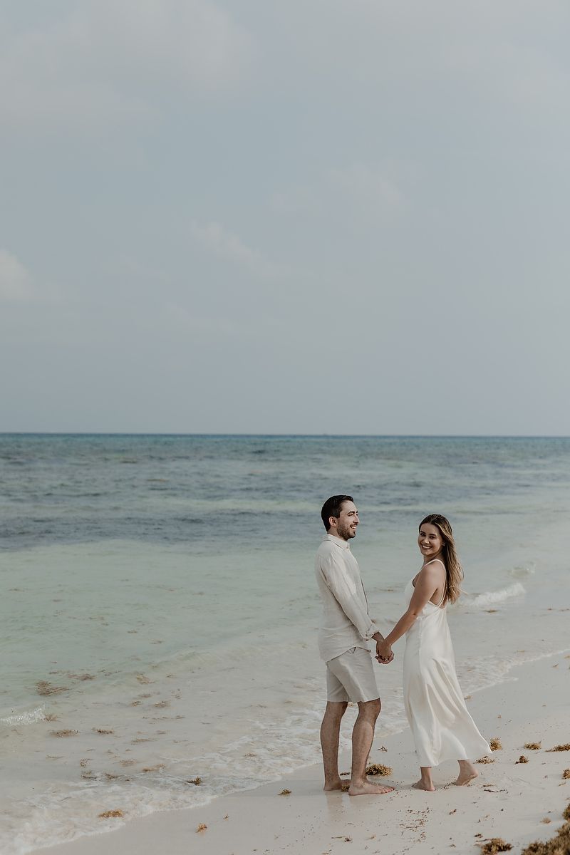 Couple walking by the turquoise Caribbean Sea during an engagement session in Playa del Carmen.