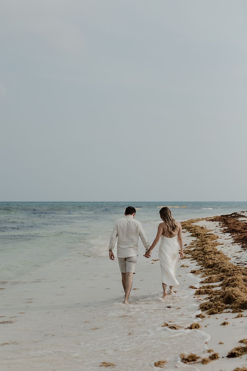 Editorial engagement portrait of a couple holding hands on the beach in the Riviera Maya.