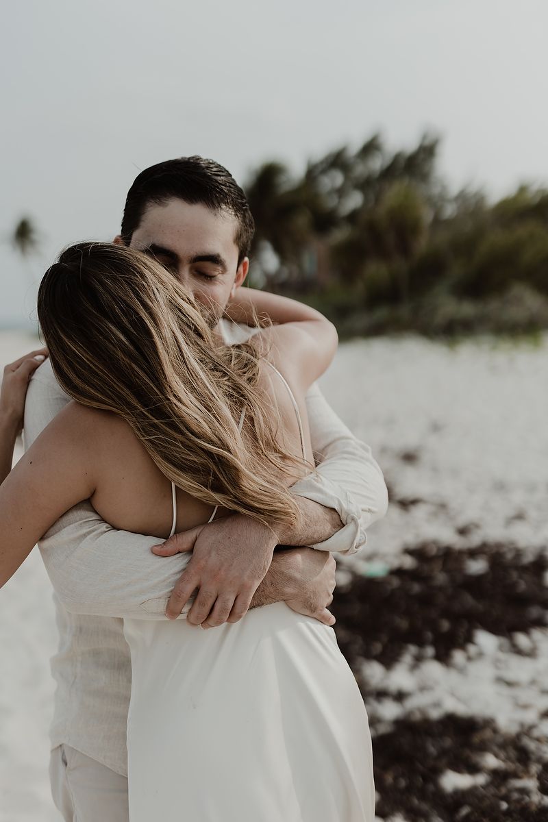 Candid embrace during a romantic engagement session at Playa del Carmen beach.