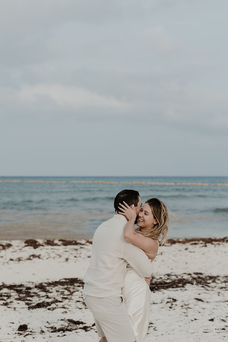 Playful engagement portrait of a couple walking along the Caribbean beach in Riviera Maya.