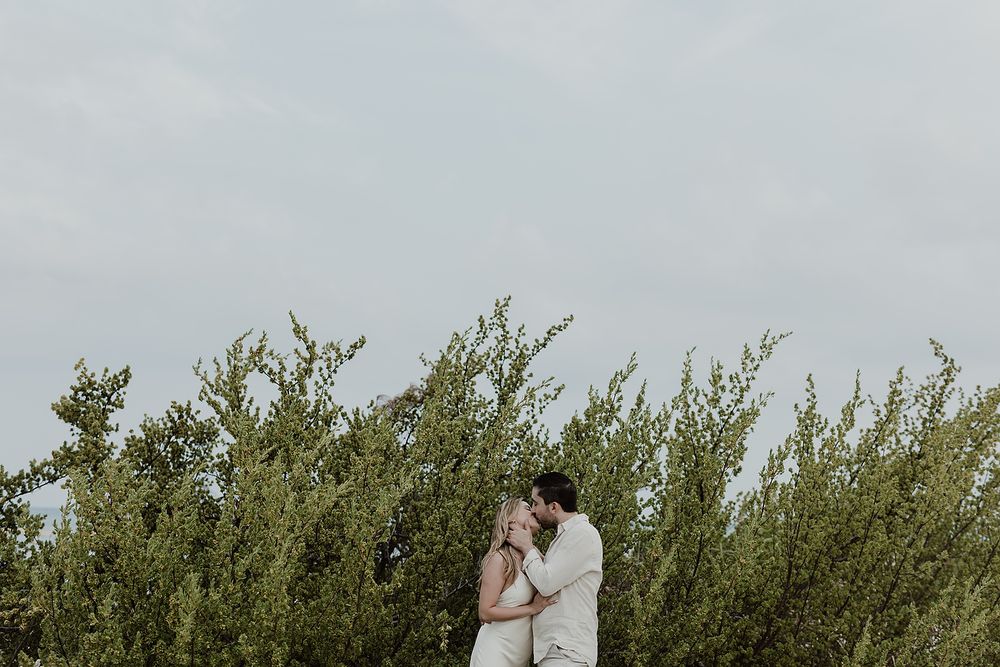 Couple kissing surrounded by tropical greenery during an engagement photoshoot in Riviera Maya.