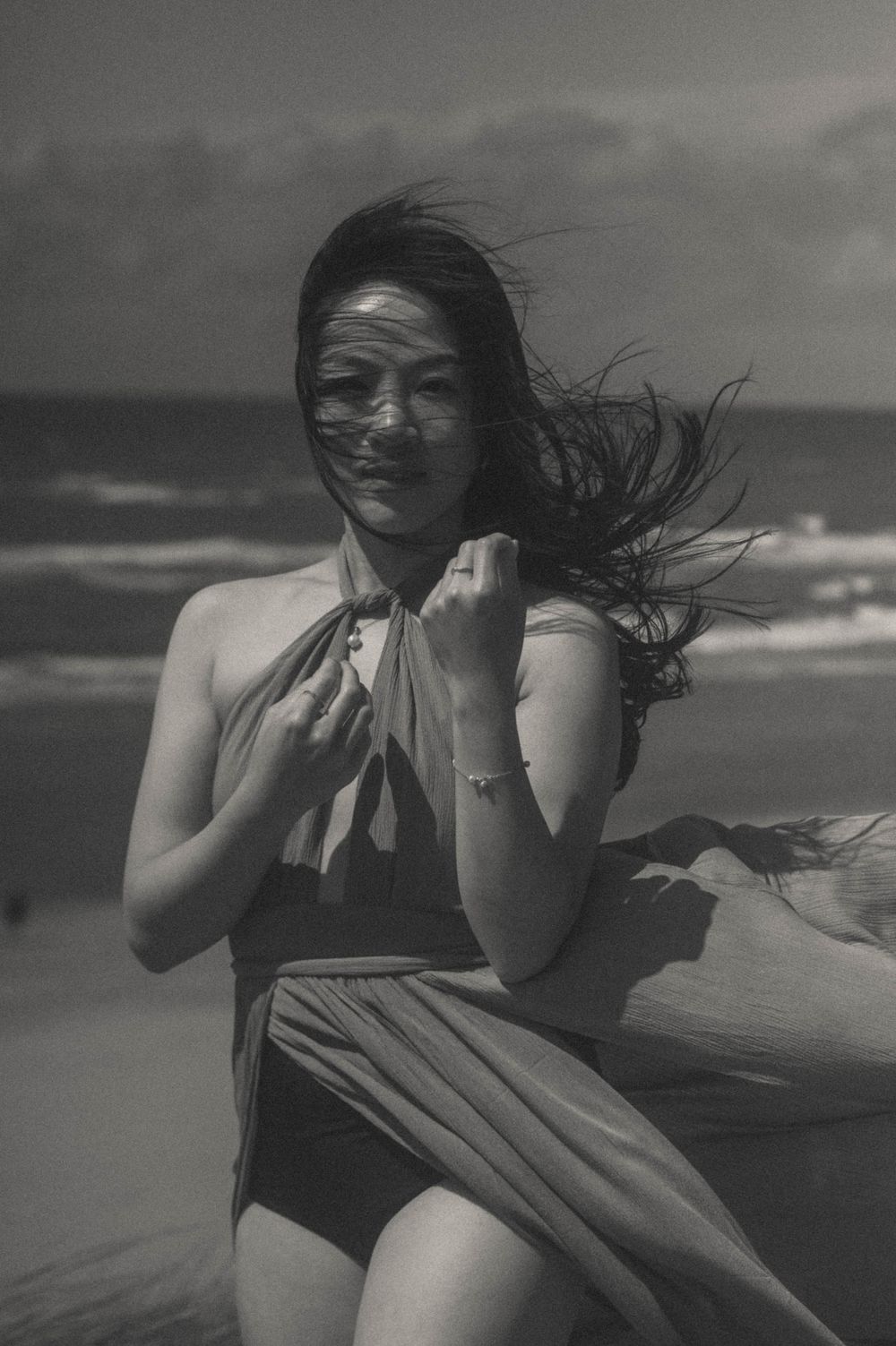 Dynamic beachside sequence showing figure in swimwear with hair blowing in coastal wind.