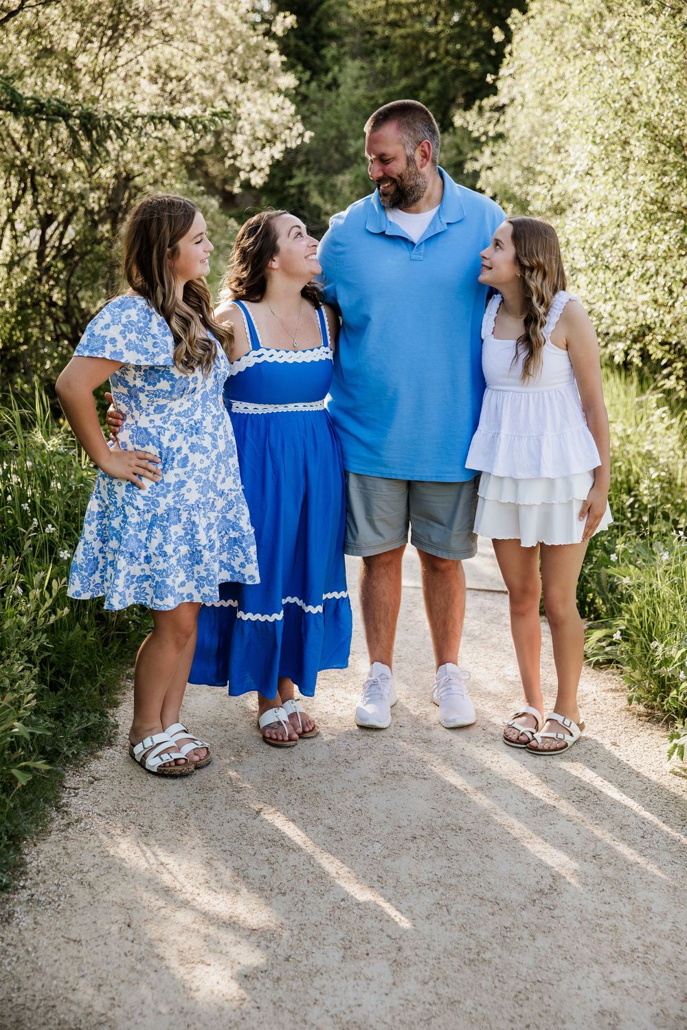Family wearing coordinated blue and white outfits standing together on a path.