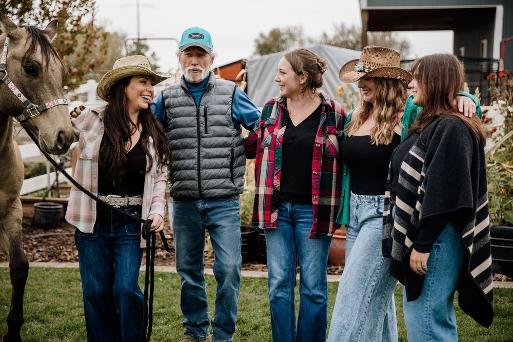 Group of friends laughing together outdoors on an autumn day wearing casual clothing.
