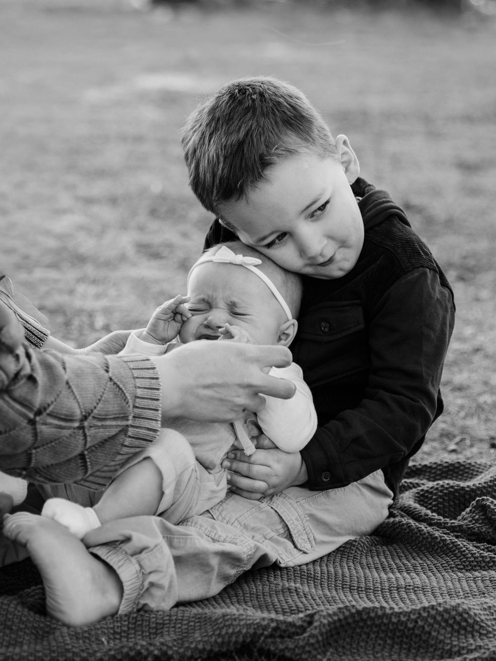 Black and white photo series showing a child lying on a blanket with a small white bunny.