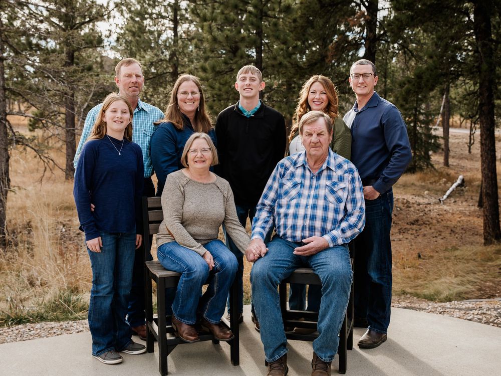 Extended family portrait series taken outdoors in a pine forest setting.