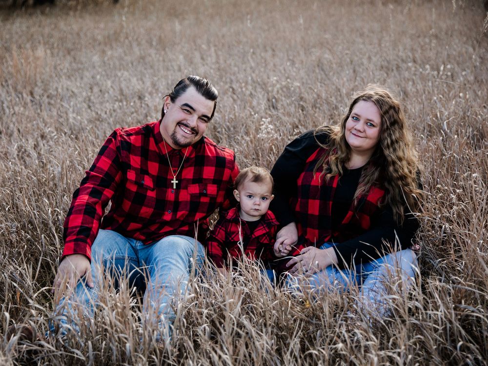 Family photo series in tall grass wearing red plaid and casual attire.
