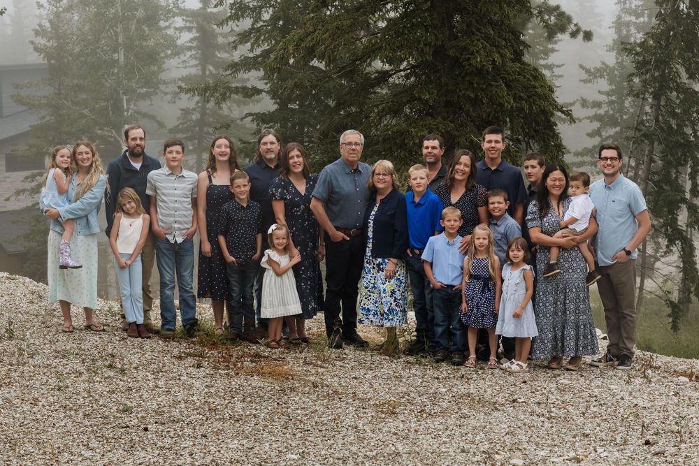 Large extended family group photo by a lake with trees in background.