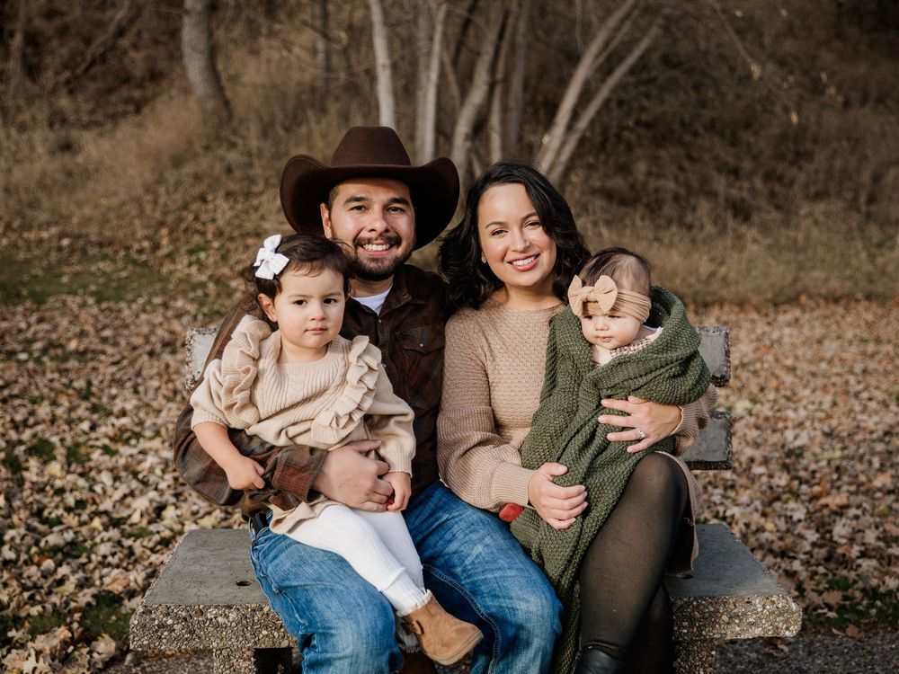 Casual outdoor family photos on log bench surrounded by fall foliage.