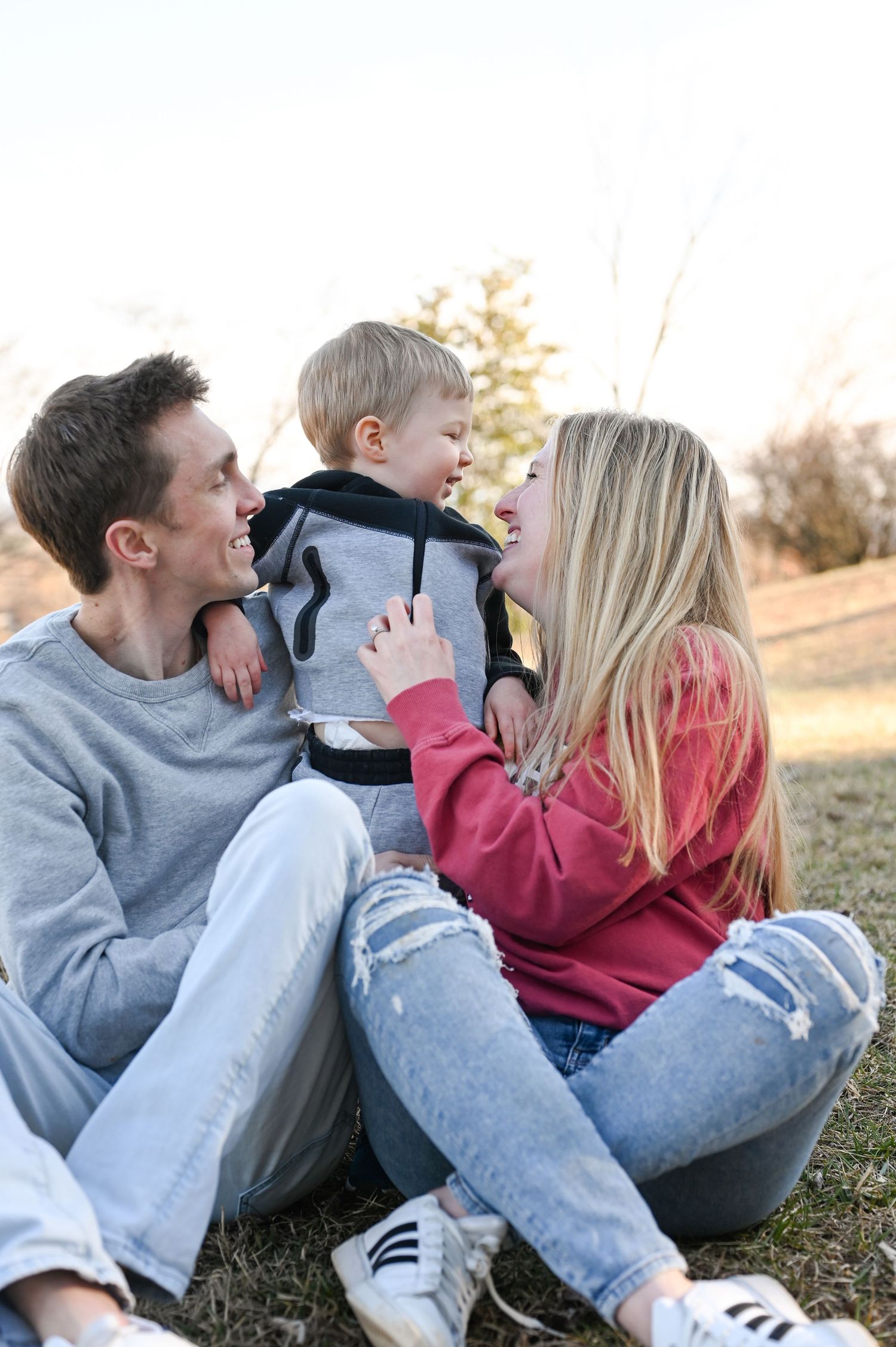 Family sharing joyful moment together on grass during golden hour photo session.