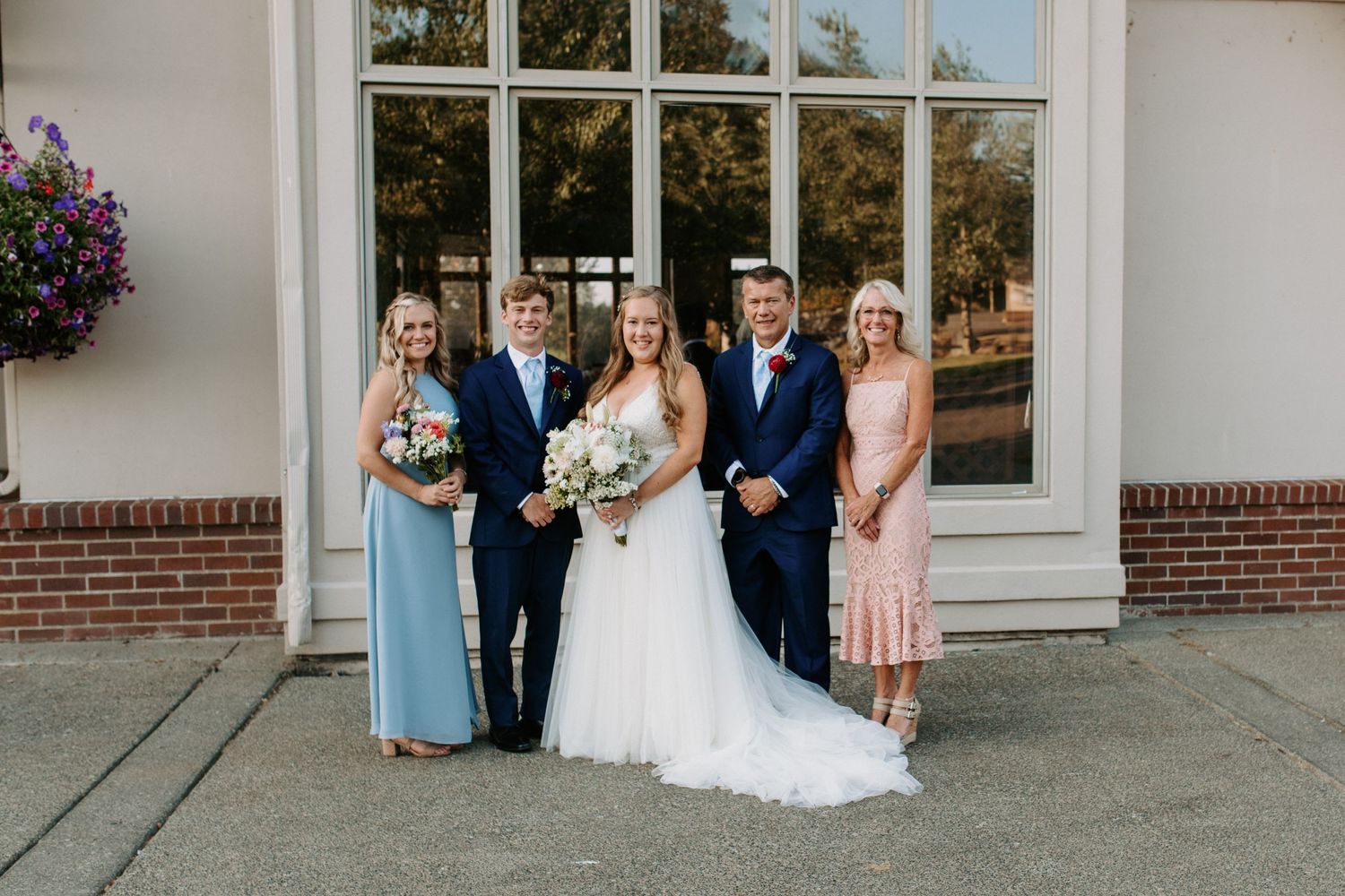 Wedding party poses outside a white church building with classic architecture.