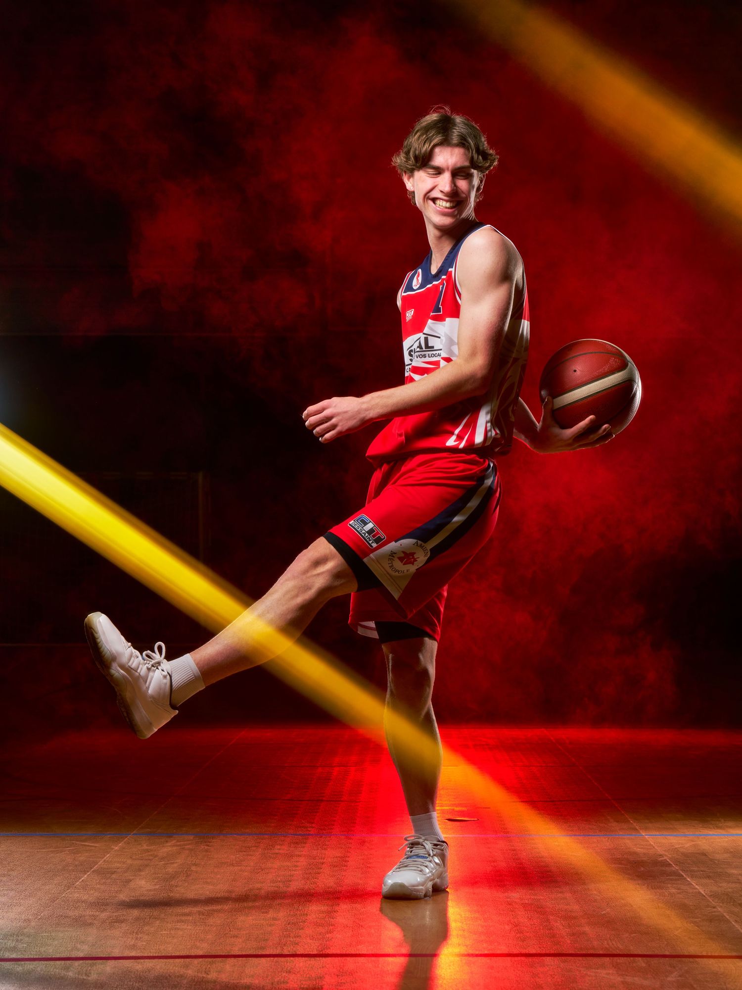Un joueur de basket-ball en uniforme rouge exécute un dribble dynamique sur une toile de fond rouge spectaculaire avec des effets de lumière
