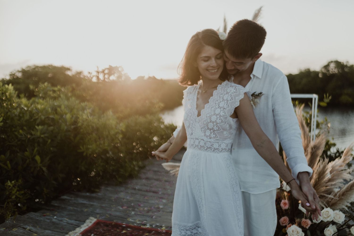 Two people in formal attire embrace near palm trees in a black and white landscape.