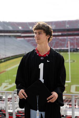 Graduate in black gown with number 1 posing at Sanford Stadium.