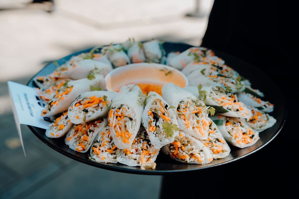 A platter of fresh rice paper spring rolls filled with vegetables and shrimp arranged in a circular pattern.