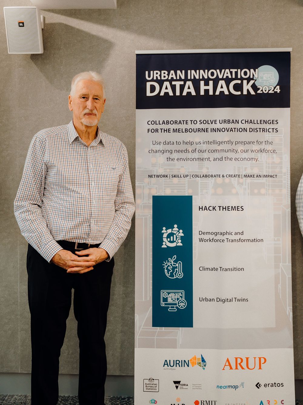 A display showing an event banner for a Data Hack 2024 innovation conference with corporate sponsor logos and themes listed.