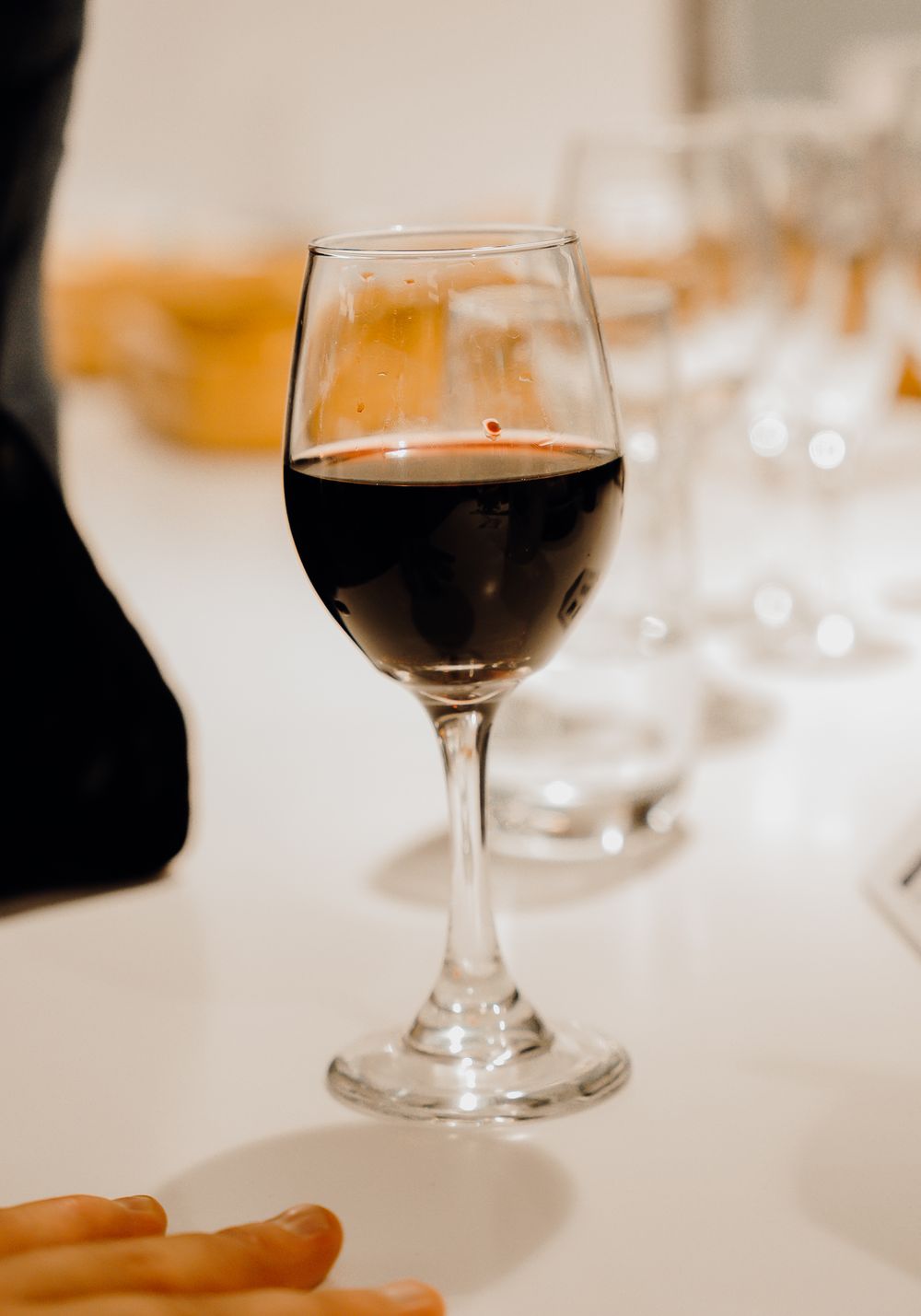 A glass of red wine sits elegantly on a white tablecloth in soft, warm lighting at a restaurant setting.