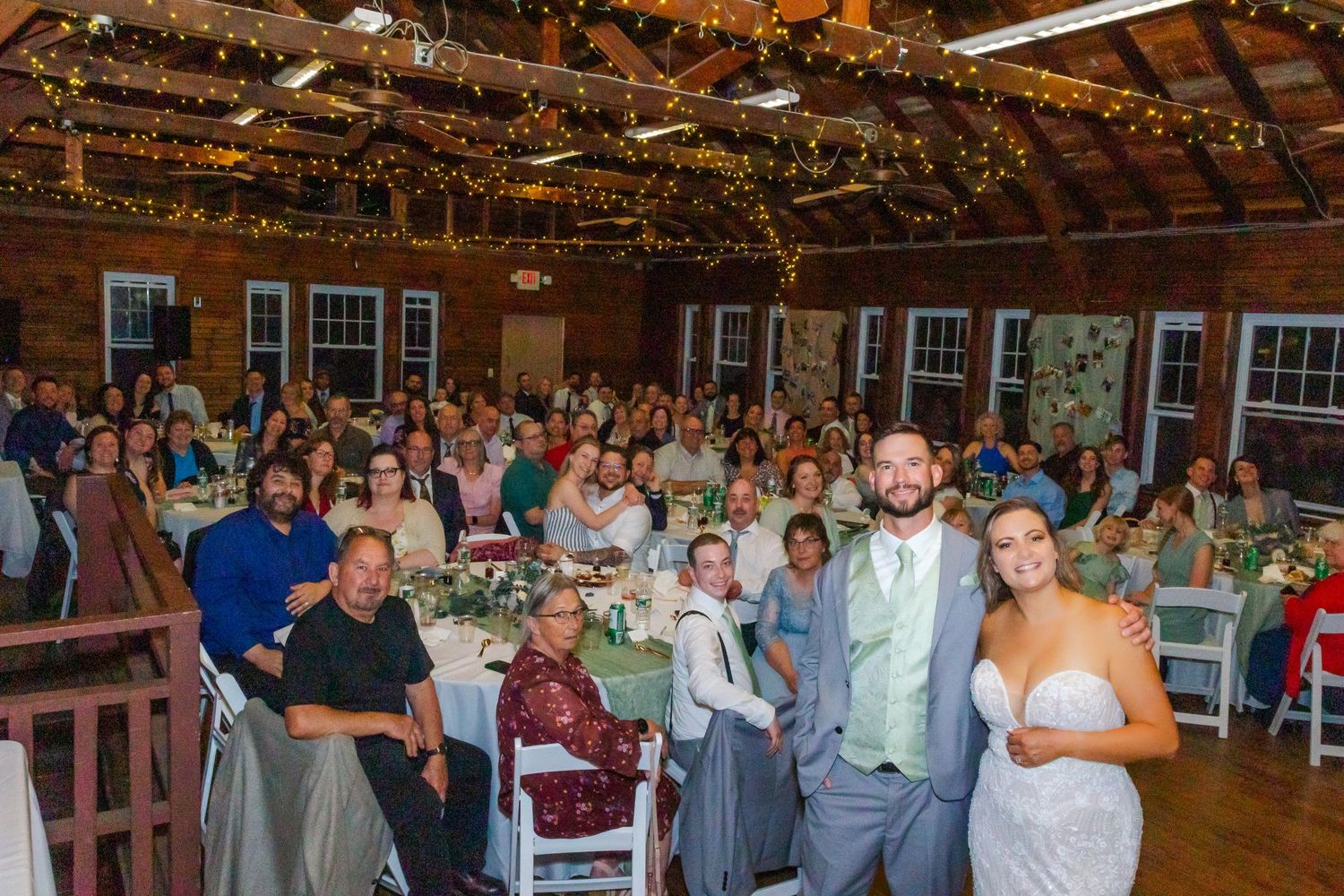 Wedding celebration in a rustic barn venue with string lights and guests gathered for reception dinner.