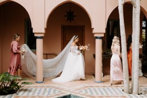 Elegant bridal moment captured in arched colonnade with flowing veil and architectural details.