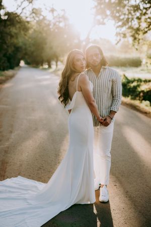 Romantic sunset portrait of newlyweds on a tree-lined path.