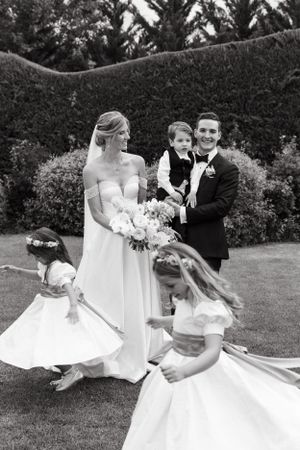 Black and white wedding portrait with flower girls twirling in white dresses.