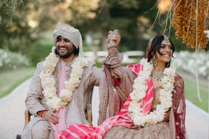 Traditional Indian wedding celebration with couple wearing ornate outfits and floral garlands.