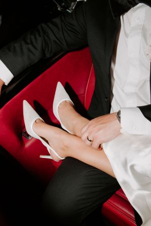 Elegant white stiletto heels resting on a luxurious red leather seat.