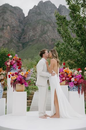 Wedding ceremony setup with colorful floral arrangements against dramatic mountain backdrop.