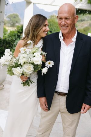 Wedding portrait with white floral bouquet against mountain backdrop.