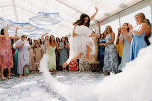 Wedding celebration scene with guests cheering during a first dance in a white tent.