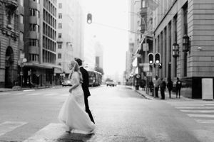 Black and white urban wedding photo on empty city street with classic architecture.