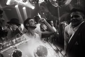 Black and white photo of energetic dancing at a wedding reception with dramatic lighting.