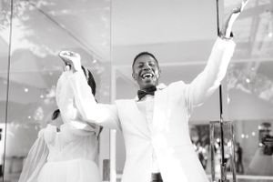 Celebrating newlyweds raise their arms in joy during their wedding reception.