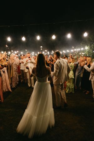 Wedding reception under string lights with guests celebrating at night.