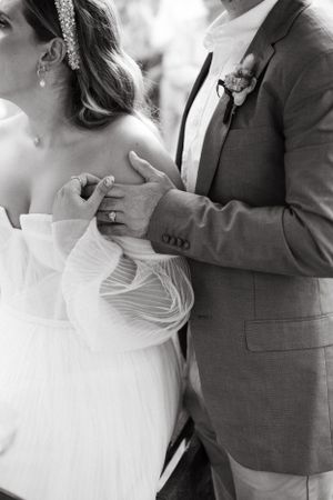 Black and white close-up of wedding couple's torso showing romantic embrace.
