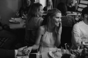 A candid black and white photograph capturing an elegant dinner reception at a wedding.