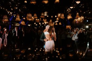 Couple shares first dance under romantic lighting with lanterns overhead.