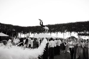 A crowd watches an aerial acrobatic performance with white smoke or fabric creating a dramatic effect.