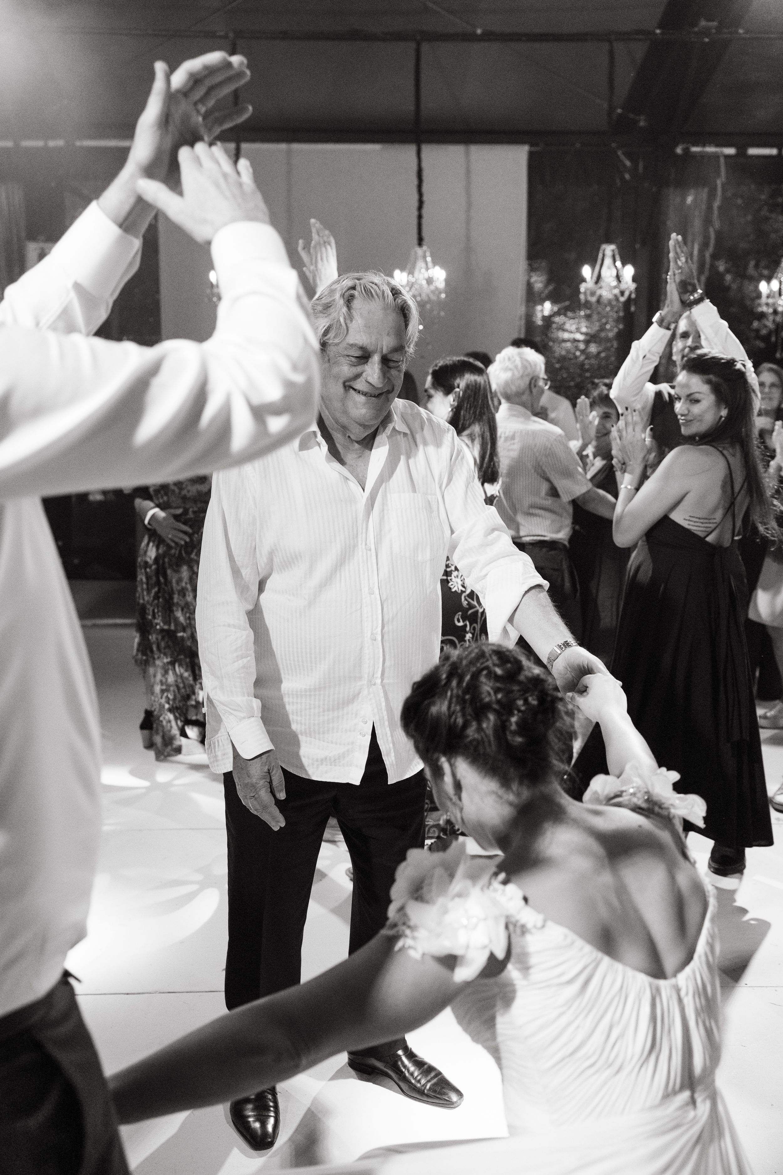 Wedding guests dancing and celebrating on the dance floor at an indoor reception.